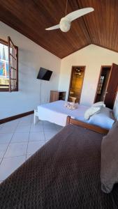 a bedroom with two beds and a ceiling fan at Casa Cacau - Guest house a 700m metros de geriba in Armacao dos Buzios