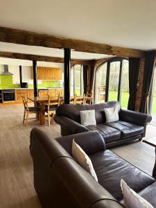 a living room with a leather couch and a table at Tove Valley Cottages in Towcester