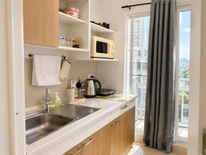 a kitchen with a sink and a microwave and a window at Apartment Phuket Old Town Fast Wifi Netflix Pool Gym Cityview in Phuket