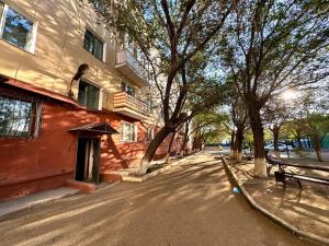 a tree lined street in front of a building at Квартира 2х ком на Амангельды 1 in Balqash