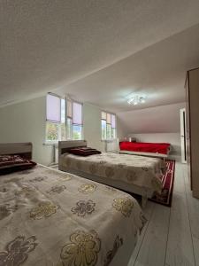 two beds in a large room with windows at Ademi Guest House in Kochkorka