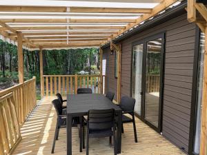 a patio with a table and chairs on a deck at Camping Le Paradis Carcans Lacanau in Carcans