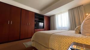 a hotel room with a bed and a flat screen tv at EXECUTIVE SUITES VALENCIA-Venezuela in Valencia