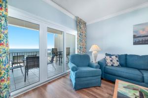 a living room with a blue couch and a balcony at Dolphin Key 3C in Orange Beach