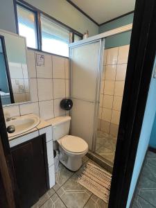 a bathroom with a toilet and a sink and a shower at Hospedaje Las Cabañas in Batán