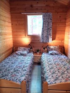 two beds in a log cabin with a window at Chalet Chez Jeannot, N6 in Mauroux +9 photos
