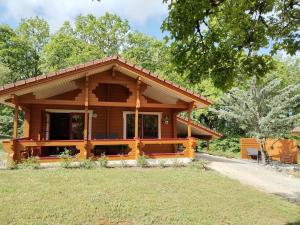 a log cabin with a large porch in a yard at Chalet Chez Jeannot, N6 in Mauroux