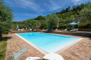 a swimming pool in a yard with chairs and umbrellas at Agriturismo Il Vecchio Casale in Vatolla