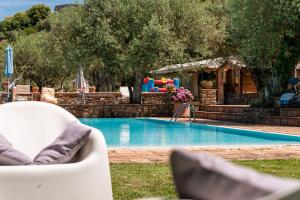 a swimming pool in a yard with a white chair at Agriturismo Il Vecchio Casale in Vatolla