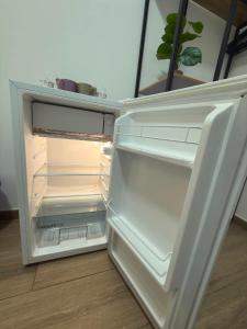 an empty refrigerator with its door open in a room at Rooms Sincelejo in Madrid