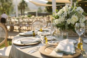 a table with plates and glasses and a vase of flowers at Radisson Collection Hotel, Bodrum in Akyarlar +139 photos