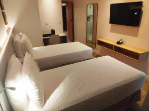 ein Hotelzimmer mit zwei Betten und einem Flachbildfernseher in der Unterkunft Holanda Gold Hotel Praia de Tambaú in João Pessoa