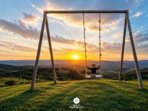 a boy sitting on a swing at sunset at Rancho Sol Poente - Rancho Queimado - SC in Rancho Queimado
