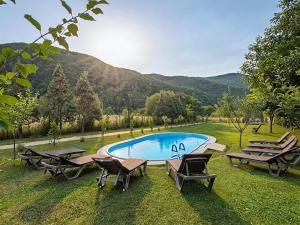 a pool with tables and chairs in the grass at Садиба в горах in Solochyn