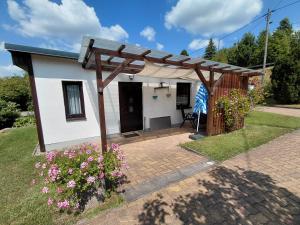 a small white house with a wooden pergola at Ferienwohnung Jahner in Reinhardtsdorf