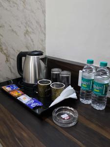 a tray with a tea kettle and bottles of water at Hotel Vihara Inn in Bangalore