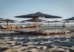 a beach with umbrellas and lounge chairs and the ocean at Casa in Durrës