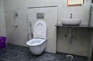 a bathroom with a white toilet and a sink at Hotel Vihara Inn in Bangalore