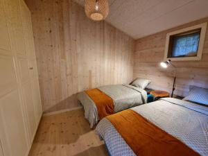 two beds in a room with wooden walls at Forest Lodge Ryokan in Trosa