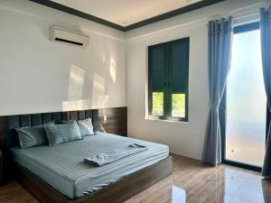 a bedroom with a large bed with a window at Captain's Home Phong Nha in Phong Nha