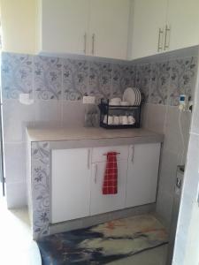 a kitchen with white cabinets and a red tie at BnB in Homa Bay +14 photos