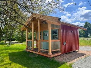 a tiny house in a yard with a red at Farma Bláto - Apartmány Sýpka a glamping in Uhlířské Janovice