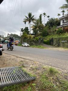 a person riding a motorcycle down the street at Sleek Haven Dormitory in Meppādi
