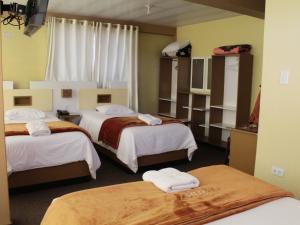 a hotel room with three beds with towels on them at Kaaro Hotel Puno in Puno