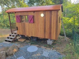 a wooden tiny house with a red roof at Roulotte à figeac in Figeac