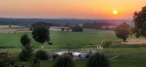 a sunset over a green field with the sun setting at Gauguin in Douzains