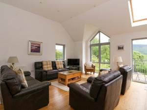 a living room with leather couches and a tv at Craigard in Aberfeldy