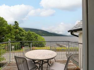 a table and chairs on a balcony with a view of the water at Craigard in Aberfeldy