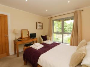 a bedroom with a bed with a desk and a window at Craigard in Aberfeldy