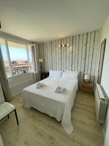 a bedroom with a large white bed and a window at CASA LAS OLAS DE LANGRE in Langre +19 photos