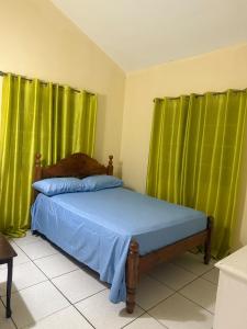 a bedroom with green curtains and a bed with blue sheets at Bella Casa in Kingstown