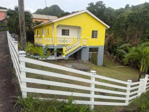 a yellow house with a white fence in front of it at Bella Casa in Kingstown