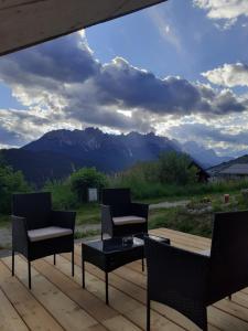 three chairs and a table on a deck with mountains at Affittacamere Sbulìa in Santo Stefano di Cadore