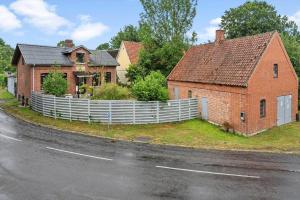 a red brick house with a white fence on the side of a road at 4025-Borre-Liselundvej-20 in Borre