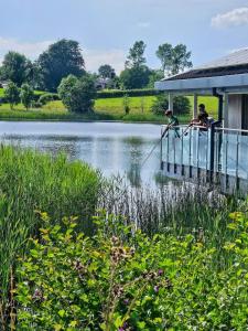 two people sitting on a dock near a body of water at The Little Green Hideaway in Fivemiletown