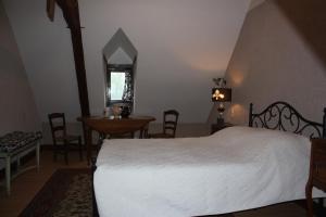 a bedroom with a bed and a table and chairs at Le Jardin Aux Lilas in Cadrieu