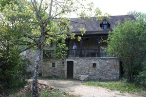 a man standing on the balcony of a stone house at Le Jardin Aux Lilas in Cadrieu