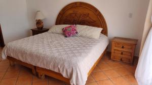 a bedroom with a large bed with a wooden headboard at Beach Condo 7- Upper Floor near Balandra fast WiFi in La Paz +21 photos