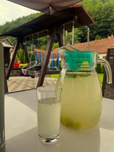 a jug of lemonade and a glass of water on a table at La Turcu in Văliug
