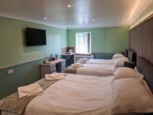 a room with four beds and a television on the wall at Moorside Hotel and Cafe in Stoupe Brow