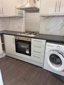 a kitchen with a stove and a washing machine at Sunny Cottage in Camborne