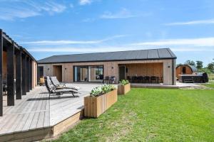 a backyard with a wooden deck and a house at 30454-Odder-Saksild-Strandfaelled-51 in Dyngby