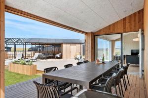a dining room with a table and chairs on a deck at 30454-Odder-Saksild-Strandfaelled-51 in Dyngby