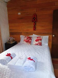 a bed with white sheets and red bows on it at Cabañas La Cima Del Cielo in San Vicente de Chucurí +12 photos