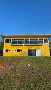 a yellow house with windows and a yard at Pousada Vale do Sol in Pariqueraçu