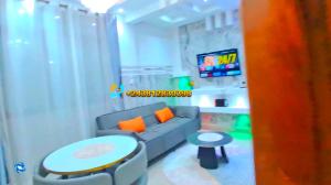 a living room with a couch and a table and a tv at Skyline Guest House in Kinshasa